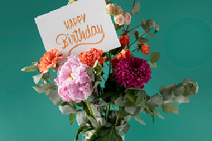Bouquet Fête du jour composé de fleurs colorées dans un vase avec une carte d’anniversaire.