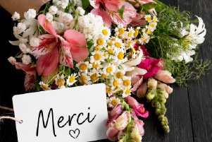 Bouquet de fleurs colorées accompagné d’une carte “Merci”.
