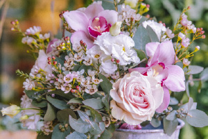 Composition raffinée composée de roses roses, orchidées et feuillage délicat dans un arrangement floral élégant