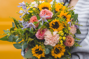 Bouquet Lumière estivale composé de tournesols, roses délicates et feuillage dans une composition chaleureuse aux couleurs d'été