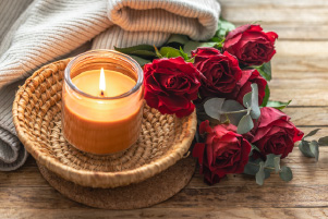 Bougie Instant cocooning aux notes florales accompagnée de roses rouges dans une ambiance chaleureuse et réconfortante